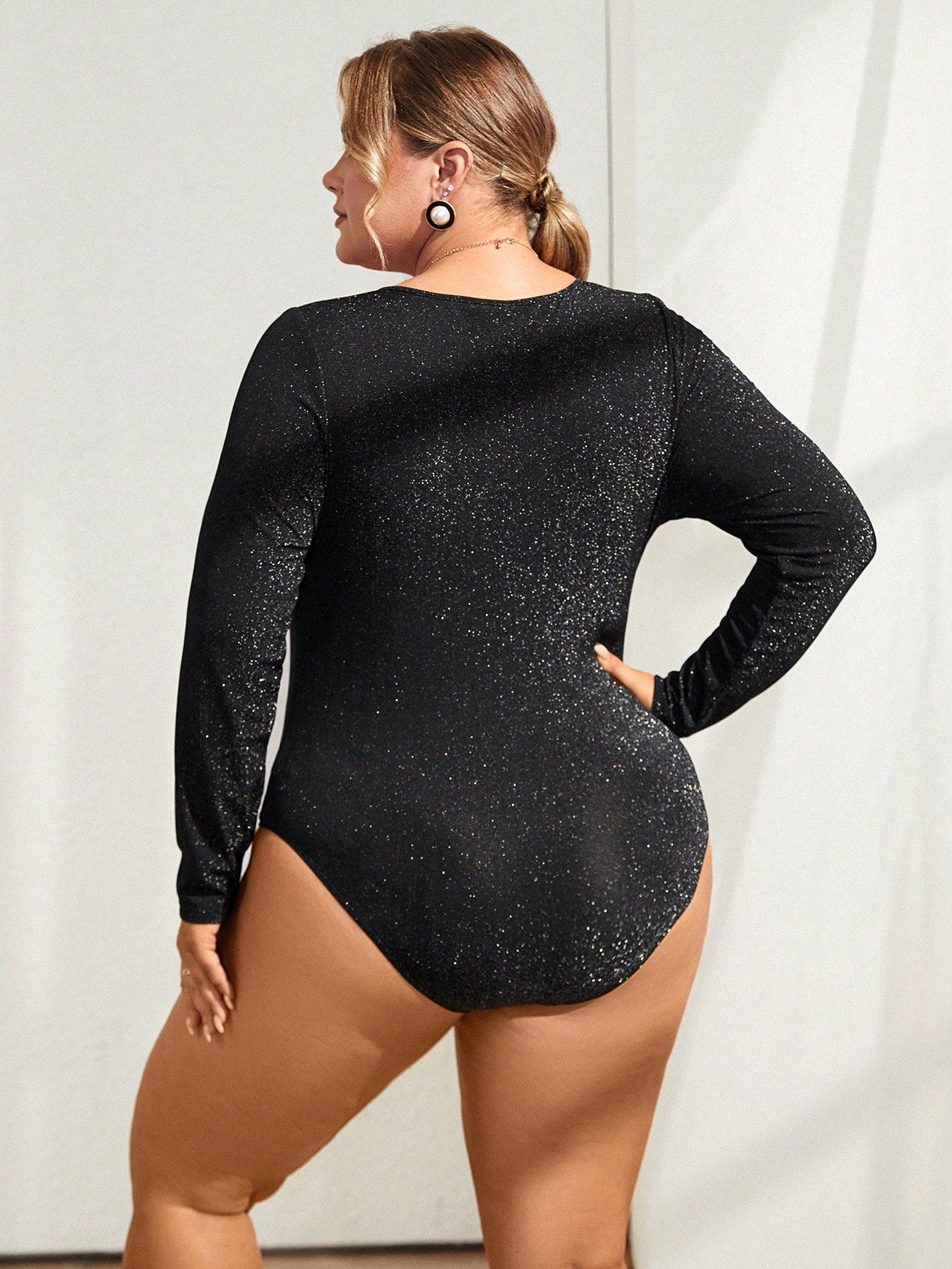 plus size model posing from behind wearing a Plus size glitter bodysuit