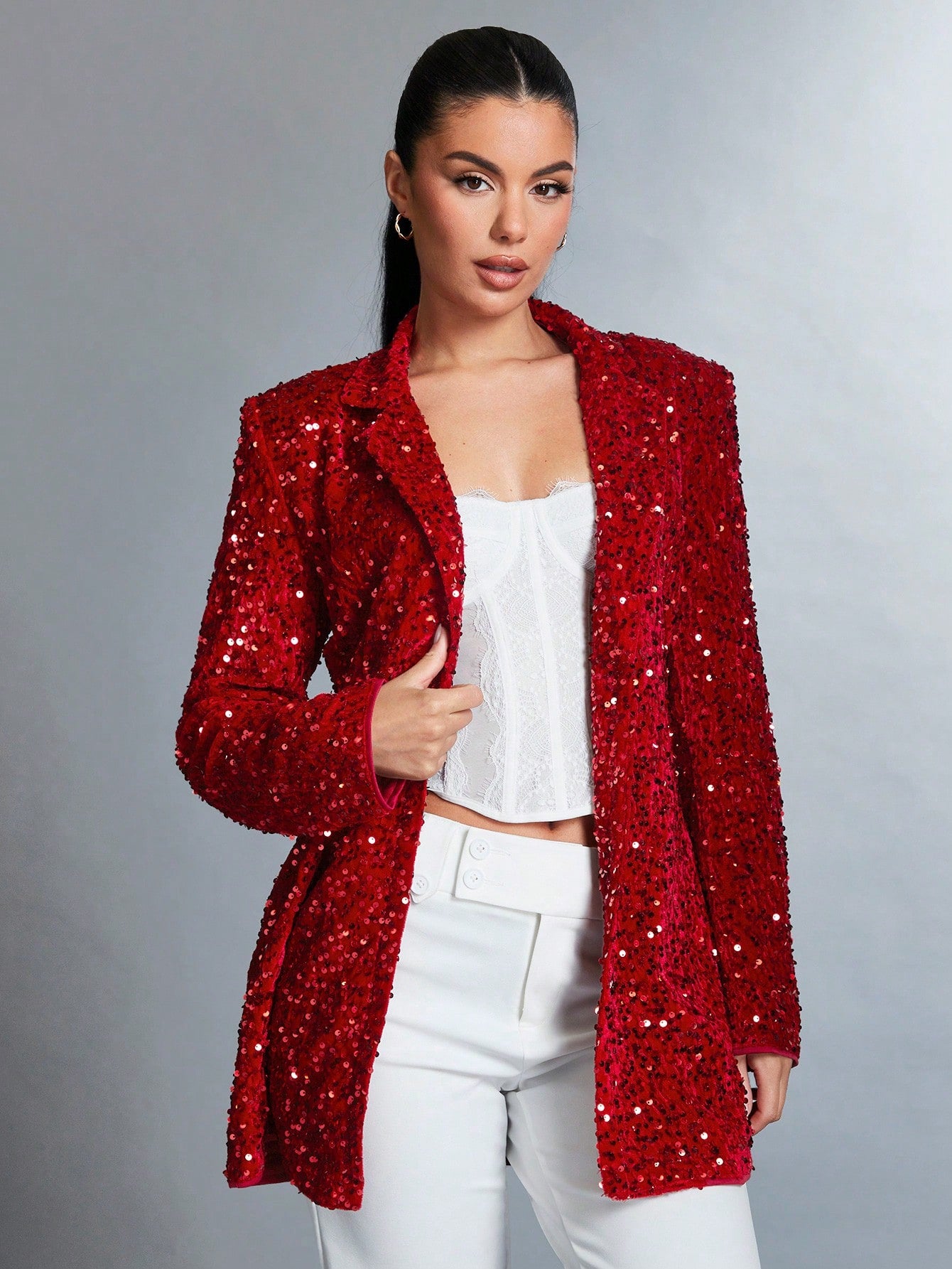 beautiful model posing for a product picture wearing a Sparkly red jacket with a white top and an elegant white pants