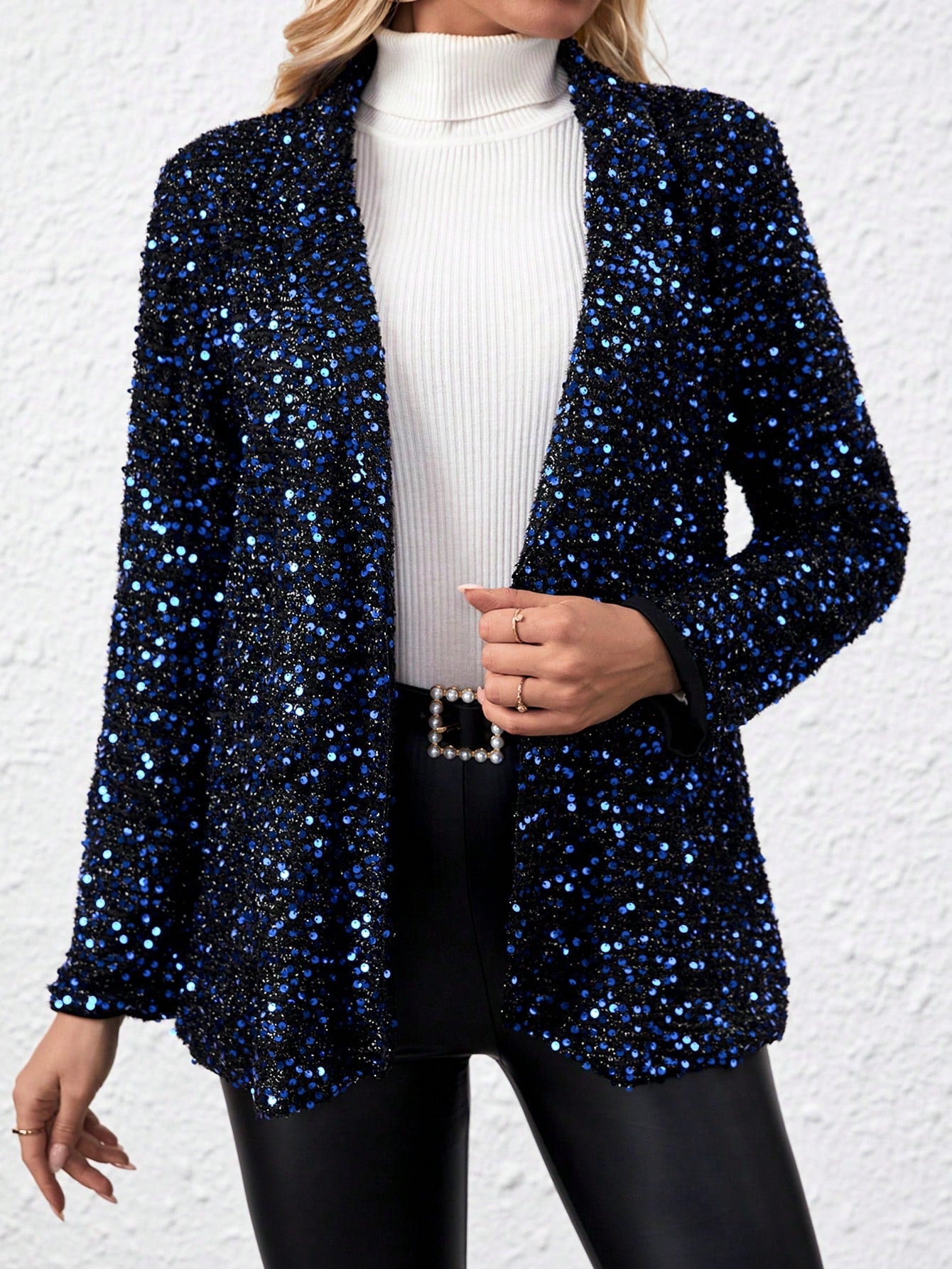 model posing with a Blue sparkly jacket, a white collar sweater and a black leather pants