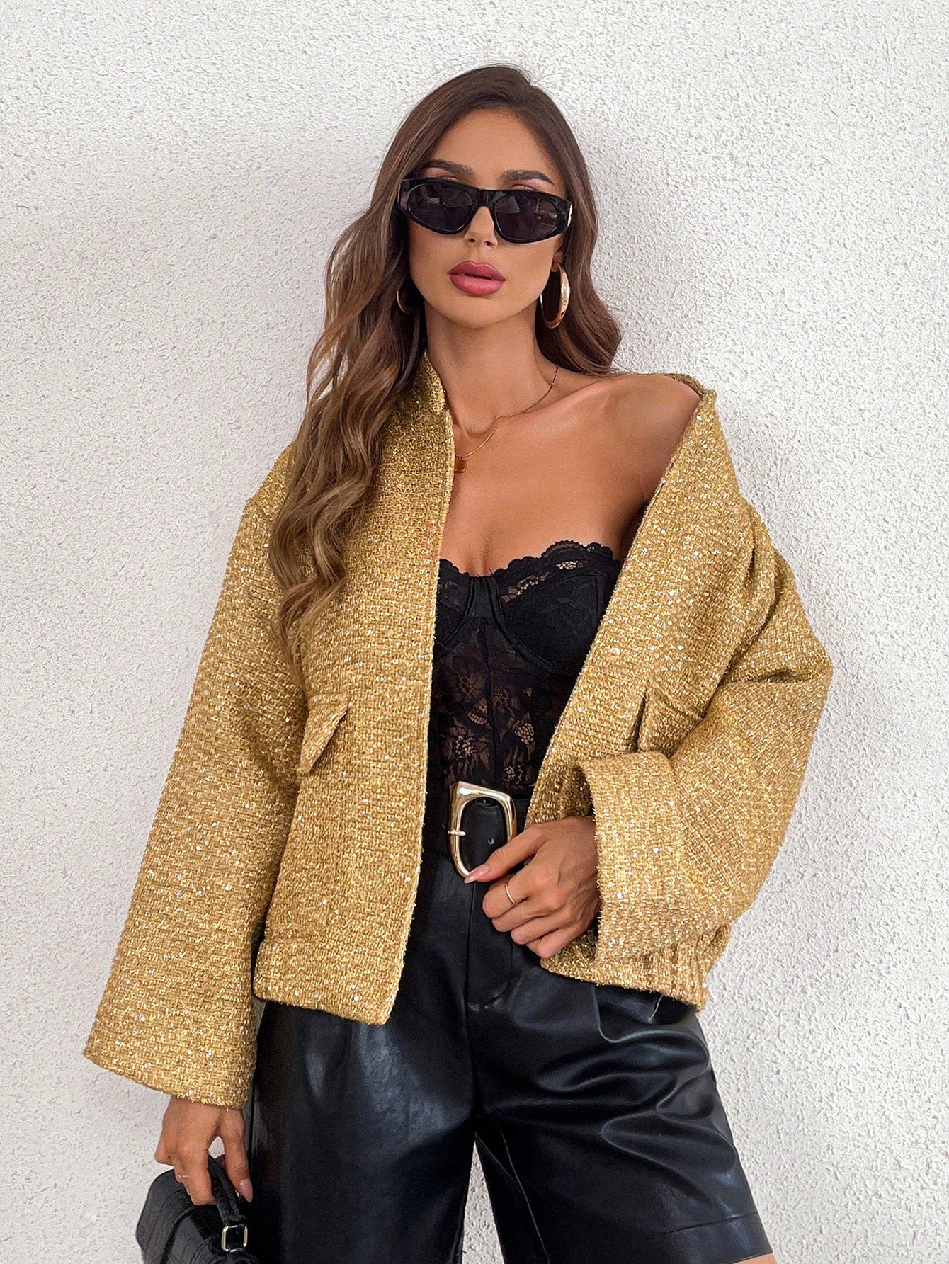 model posing for a product picture wearing a Gold sequin sleeve jacket with a black sungalsses, a black lace corset and a black faux leather pants