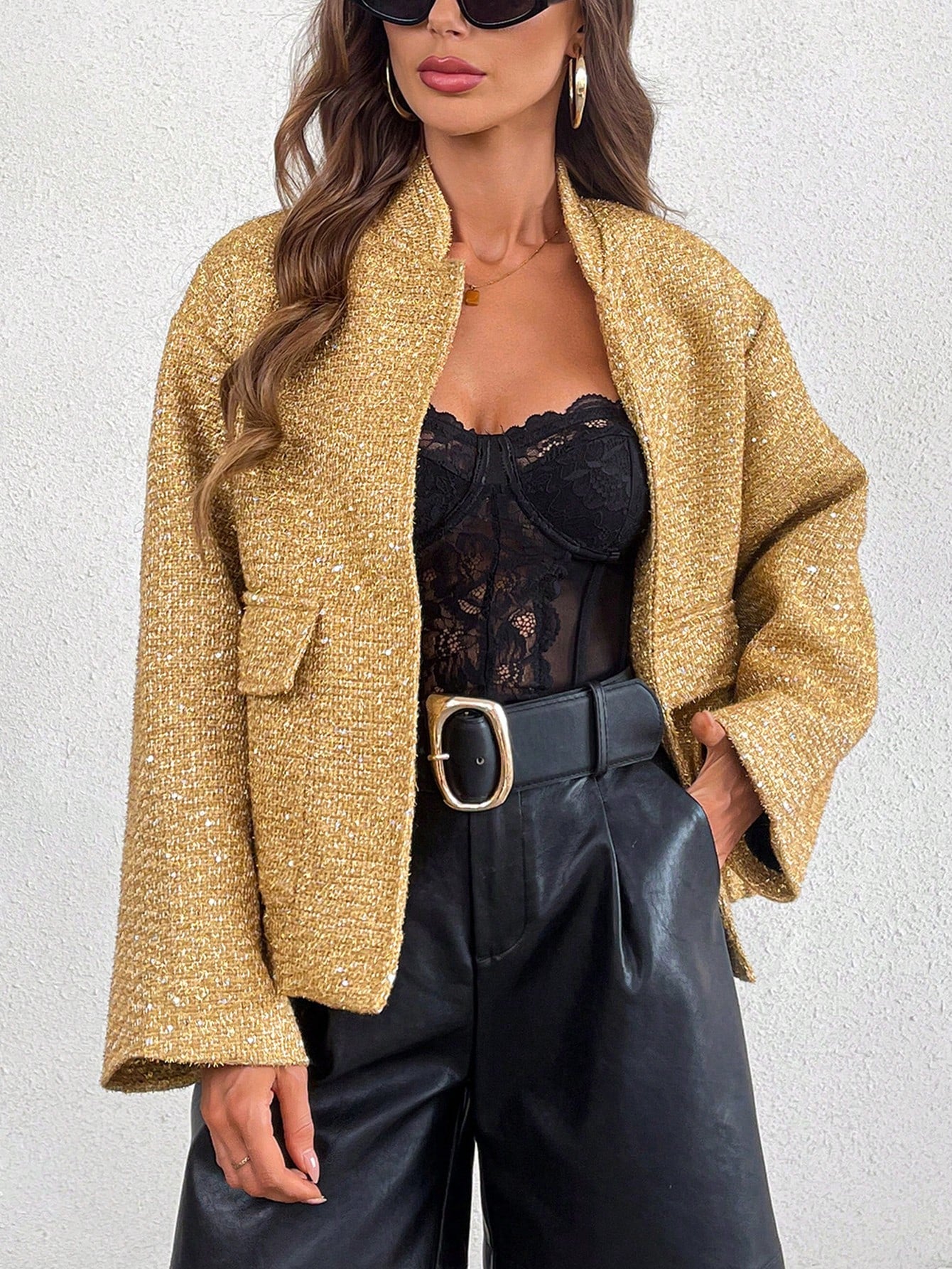 Gold sequin sleeve jacket worn by a model with a black faux leather pants for a product picture