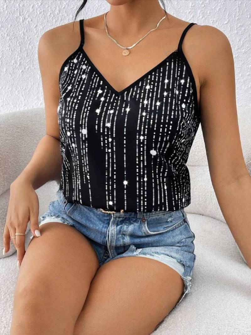 model sit on a couch wearing a Black and silver sequin tank top with a blue jeans